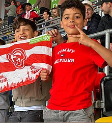 Foto: 2 Schüler halten eine Fortuna Flagge und freuen sich über ein Tor.