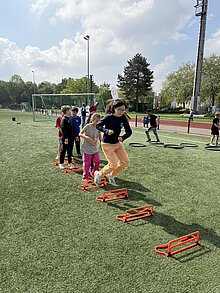 Ein Kind springt über Hürden im Laufparcours. 