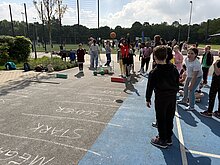 Foto: ein Kind wirft einen Medizinball über eine weit entfernte Linie.