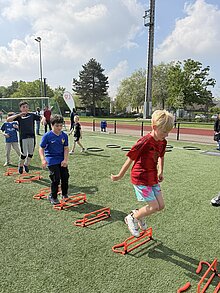 Foto: Kinder springen über Hindernisse in einem Parcours. 