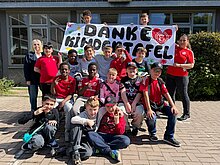 Foto: Gruppenfoto mit Dankeschild für die Kindertafel Düsseldorf.